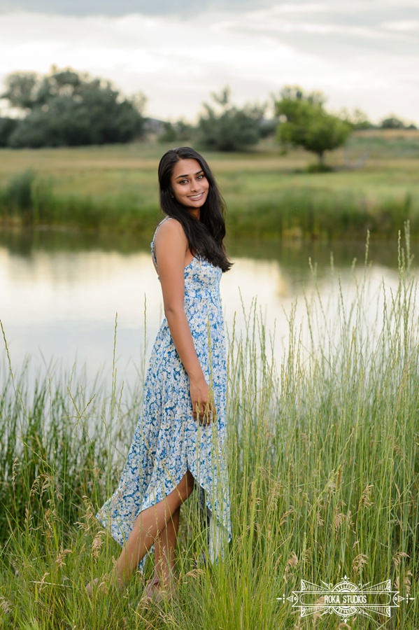 senior girl in floral dress with tall grass and lake in the background